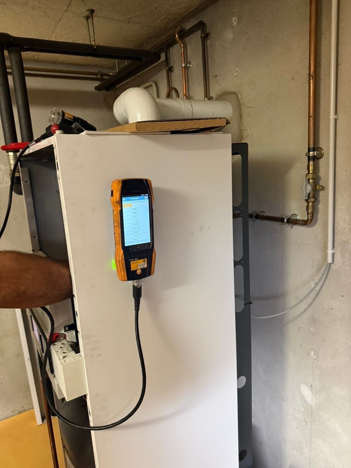 Analyseur de combustion branché sur une chaudière gaz à condensation pendant un entretien annuel